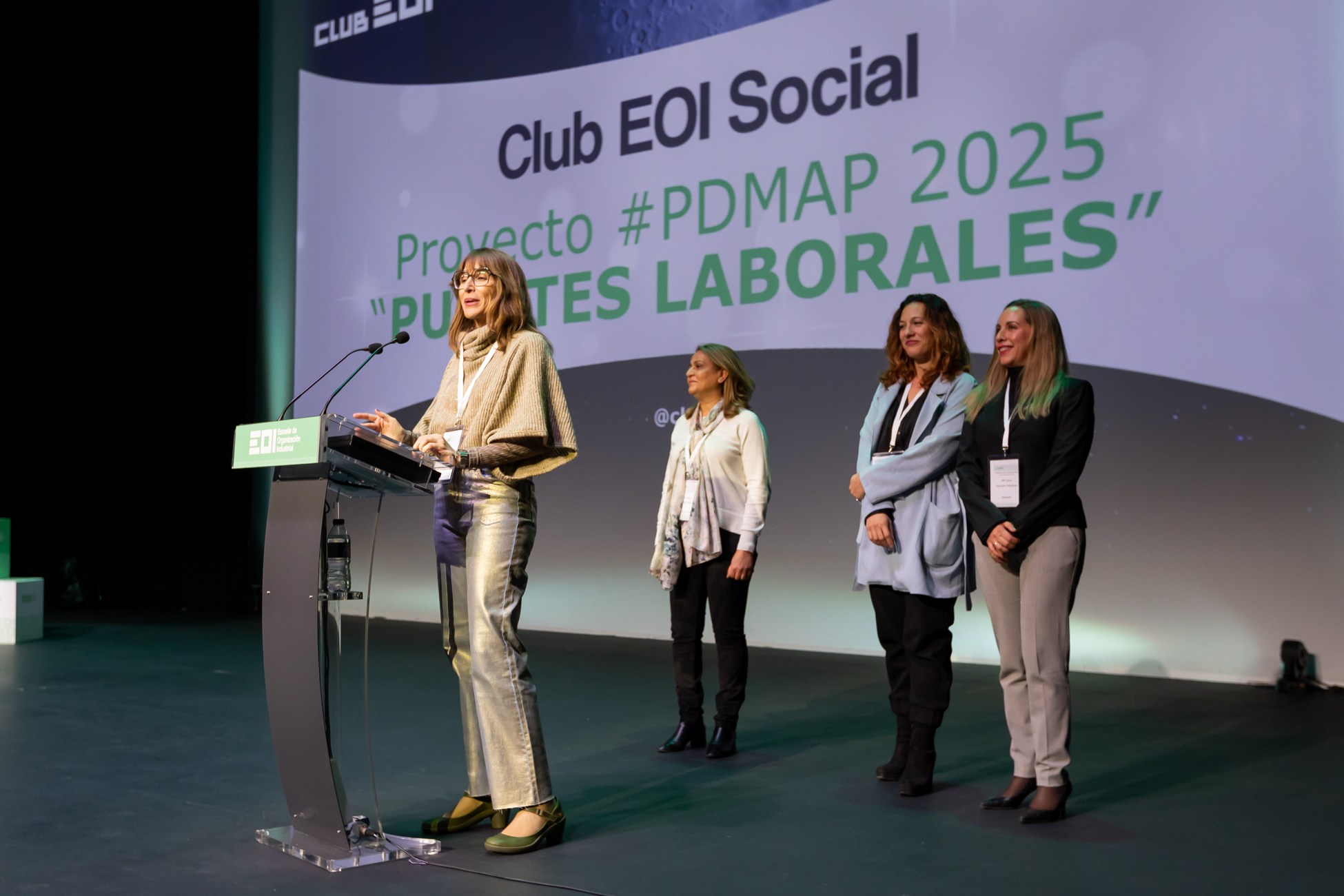 Presentación de un proyecto con tres participantes en el escenario